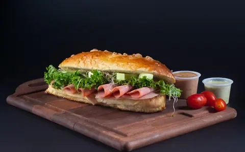 Baguette de jamón con lechuga y germen sobre tabla de madera