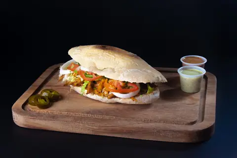 Torta de carne con jitomate, cebolla y lechuga, con jalapeños y aderezos