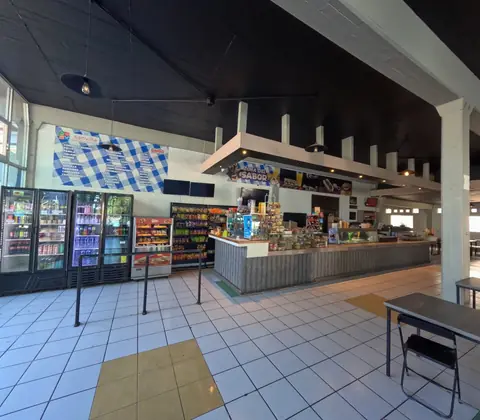Cafetería con barra de servicio, refrigeradores de bebidas y tienda de snacks