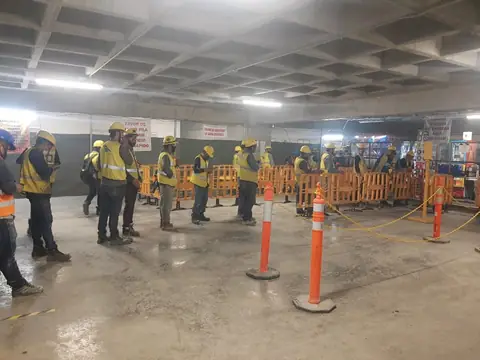 Trabajadores de construcción con casco y chaleco haciendo fila para el servicio de comida